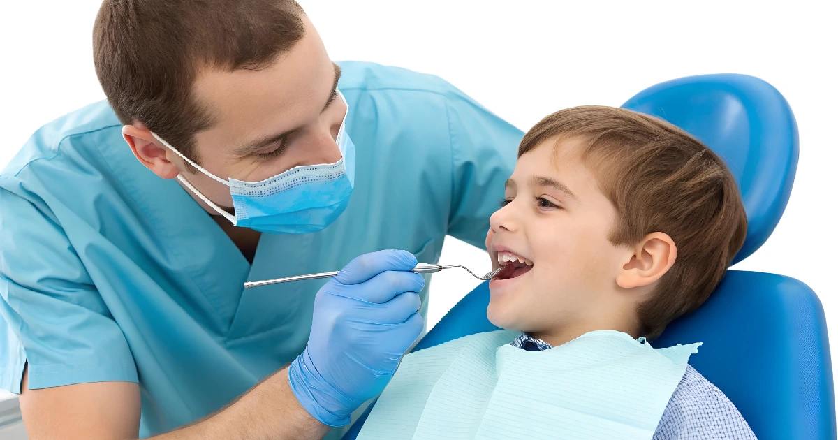 A pediatric dentist in Chandler, AZ examines a smiling child’s teeth during a dental checkup.